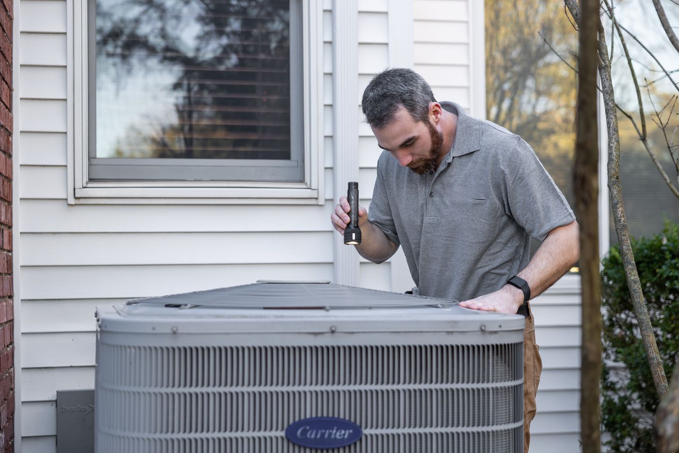 HVAC technician inspecting an outdoor air conditioning condenser
