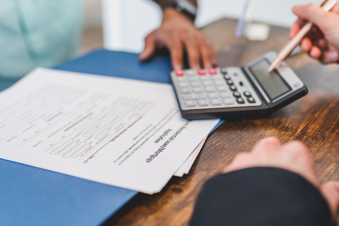 Hands working a calculator over printed financial statements on a desk