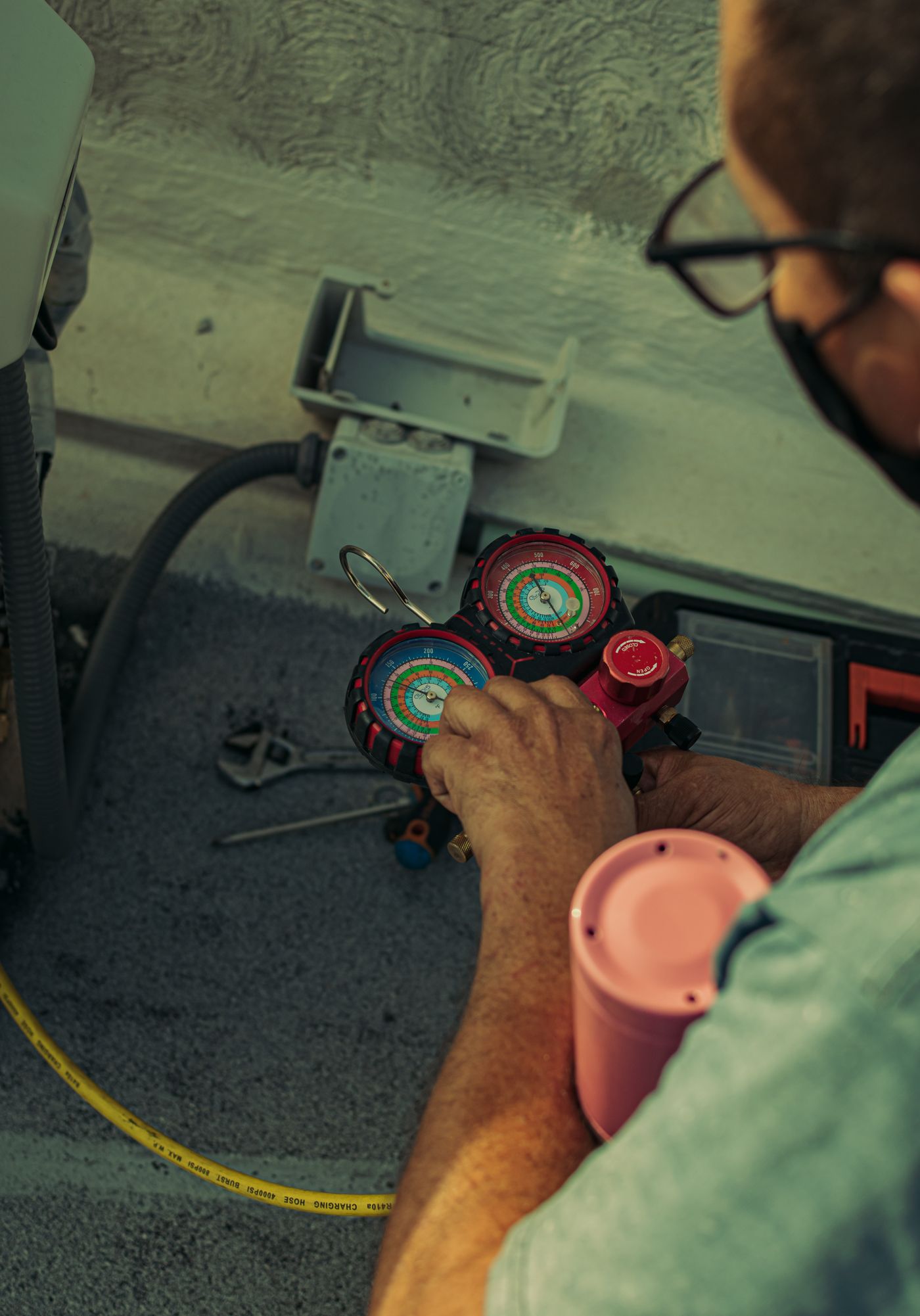 Close-up of a technician adjusting a refrigerant manifold gauge set