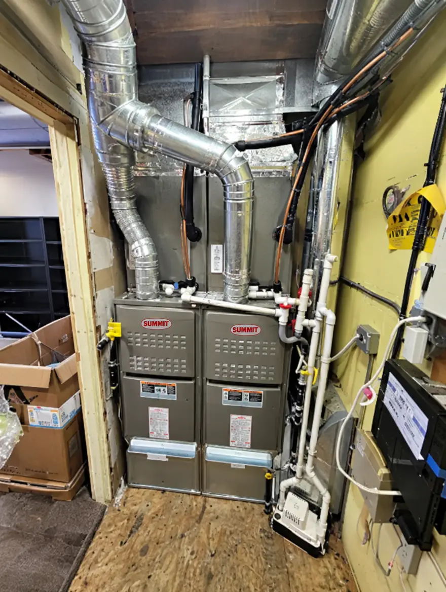 Two Summit furnaces installed side by side in a utility closet with ductwork